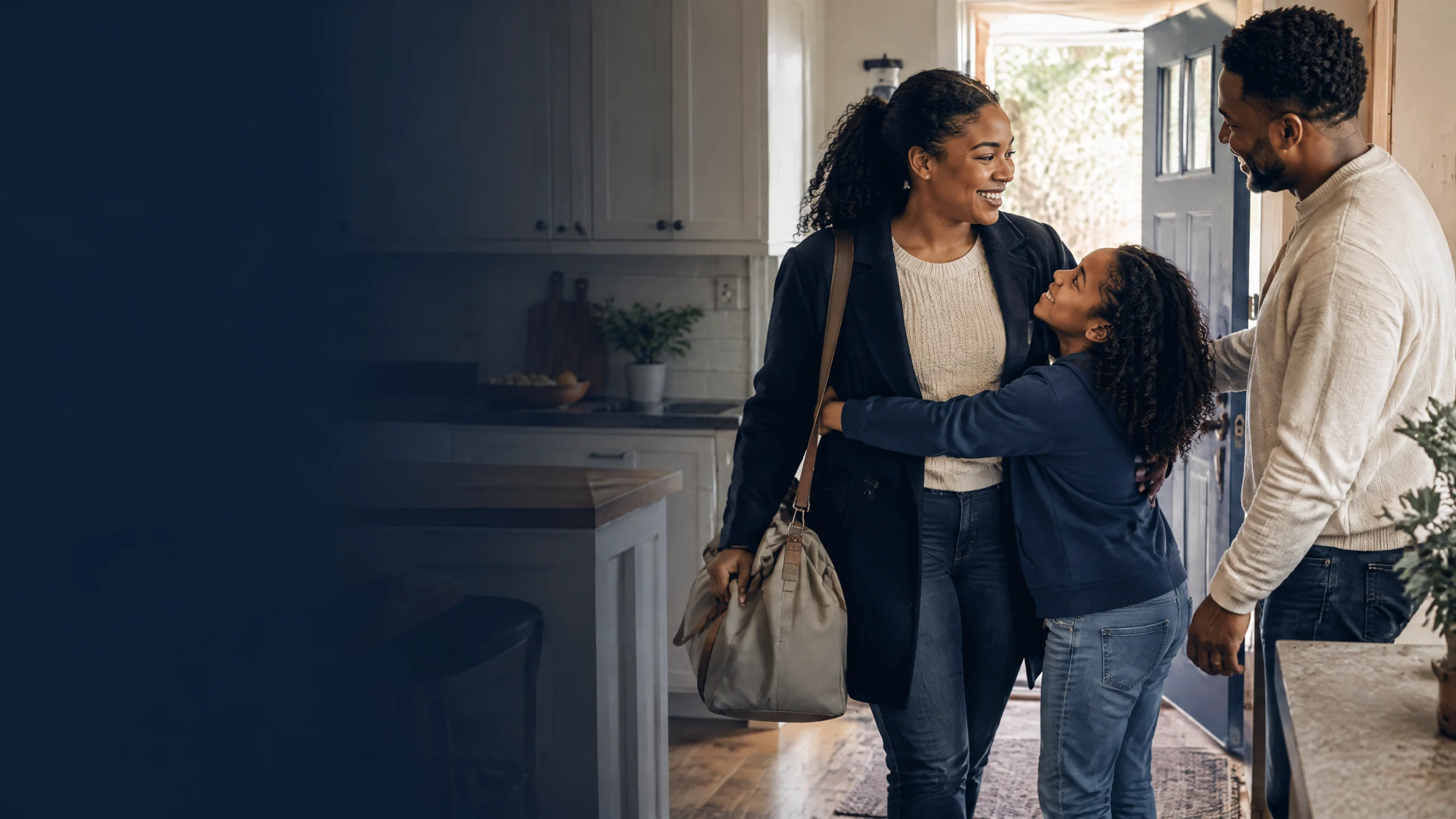 A Black woman in civilian travel clothes shares an ordinary kitchen return with her co-parent and child.